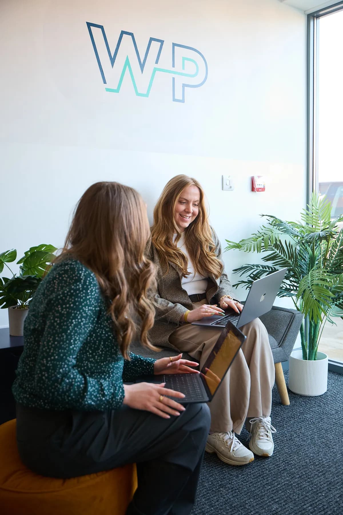 Two World Products team members working together beneath the WP logo at the office